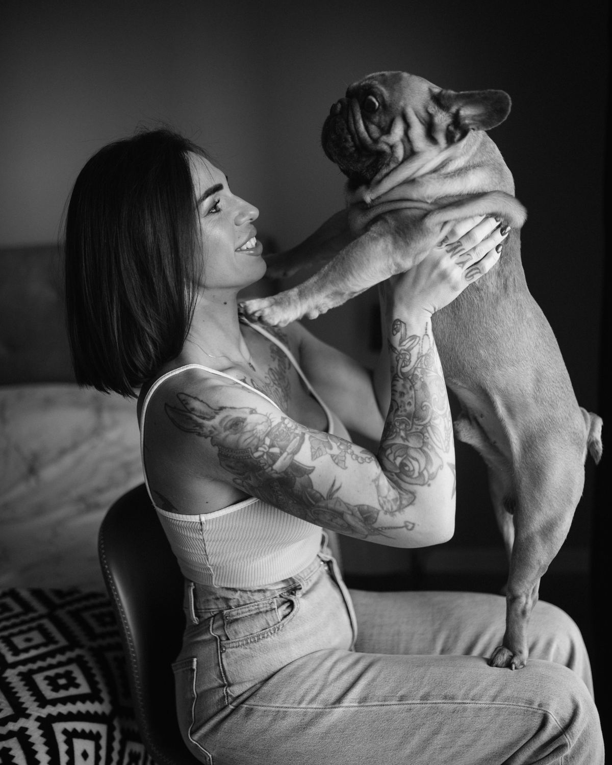 A smiling woman holds her dog up to face her.